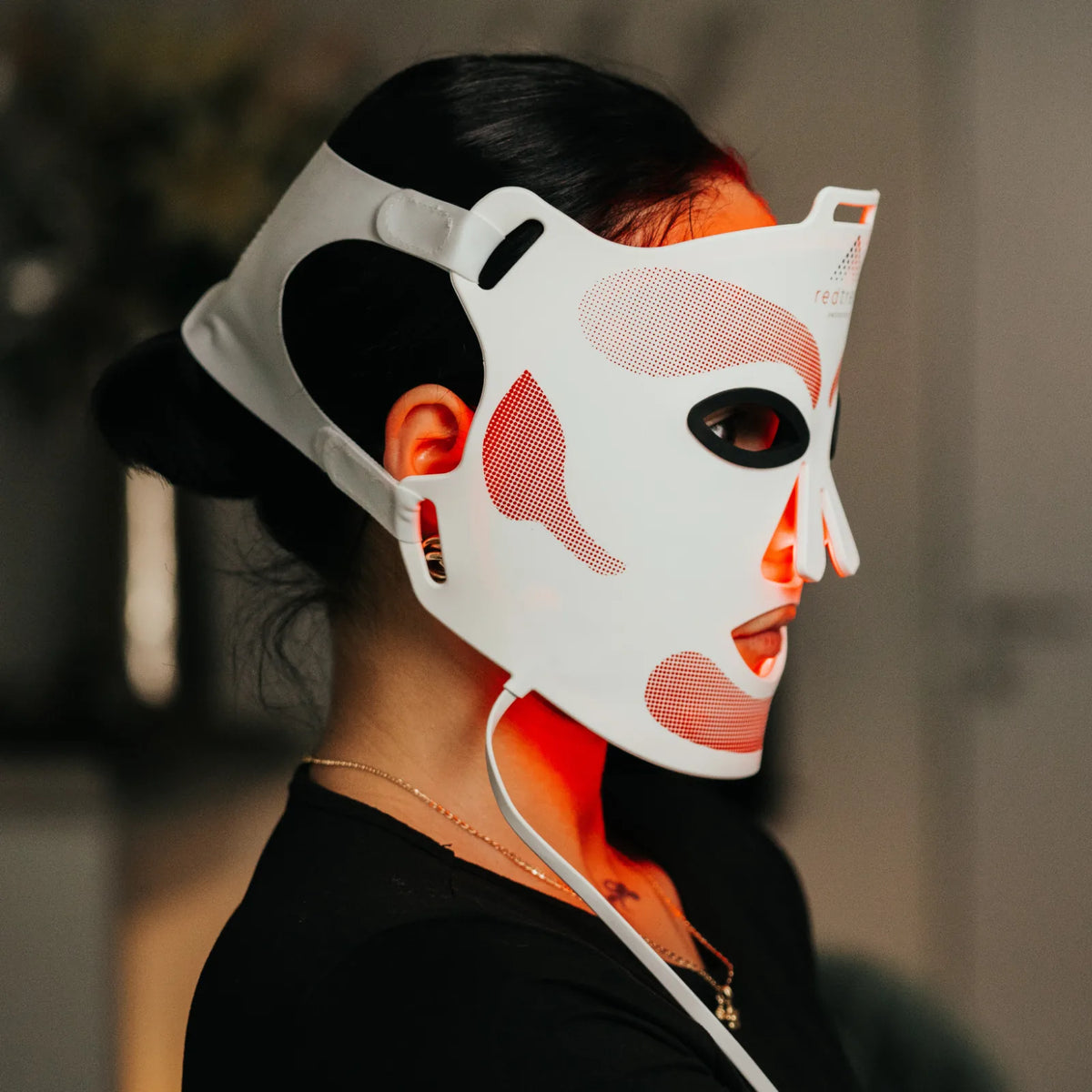 Seitenprofil mit der redtreat SolisMask am Gesicht, in der Hand die Steuereinheit der LED-Maske